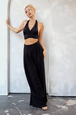 Stüdyo arka planında poz veren, siyah şık kıyafetler giyen genç, çekici sarışın manken.. 