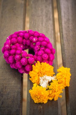 Çelenk çiçekleri kadife çiçekleri ve dünya çapındaki amaranth veya ahşap arka plandaki bekarlık düğmesinden oluşur..