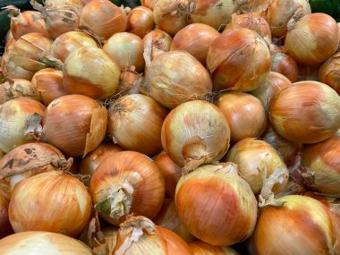 Bir markette sergilenen çiğ sarı soğan yığınları