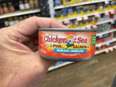Grovetown, Ga USA - 01 02 23: Grocery store hand holding Chicken can skinless salmon