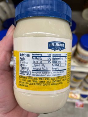 Grovetown, Ga USA - 01 13 23: Grocery store Hand holding Hellmans real mayonnaise ingredients label