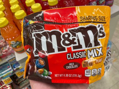 Grovetown, Ga USA - 02 17 23: Grocery store hand holding MM candy M and Ms classic mix