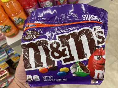 Grovetown, Ga USA - 02 17 23: Grocery store hand holding MM candy M and Ms purple bag