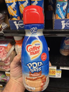 Grovetown, Ga USA - 02 17 23: Grocery store hand holding Coffeemate coffee creamer Pop tarts flavor