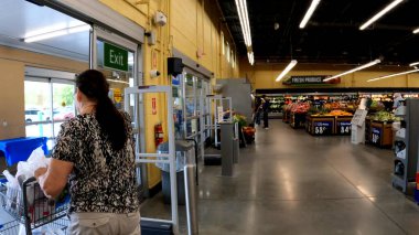 Grovetown, Ga USA - 04-21-22: Walmart 'ın içişleri bakkalı kadın el arabasını dışarı itiyor