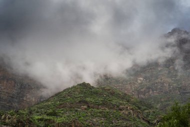 Arka planda alçak fırtına bulutlarıyla kaplı Tirajana dağları. Büyük Kanarya. Kanarya Adaları