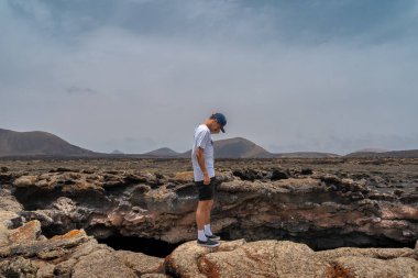 Genç adam Las Palomas Mağarası 'nın girişine bakıyor. Timanfaya Ulusal Parkı. Lanzarote. Kanarya Adaları
