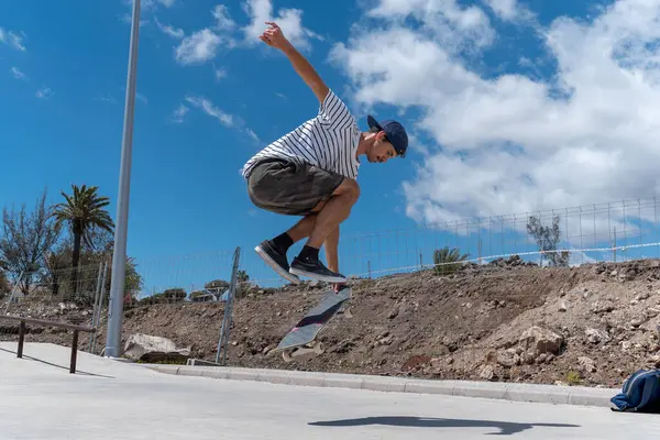 Genç adam güneşli bir günde kaykay parkında paten kayıyor.