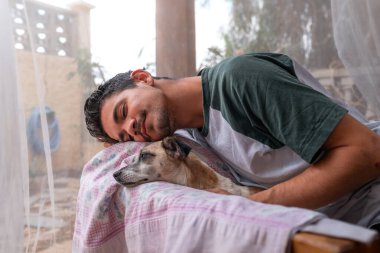 Genç adam bahçede sıradan bir köpekle etkileşime girer.