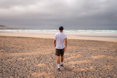 Genç adam Famara plajını ziyaret ediyor. Teg giyin. Lanzarote. Kanarya Adaları. İspanya