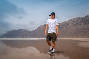Genç adam Famara plajını ziyaret ediyor. Teg giyin. Lanzarote. Kanarya Adaları. İspanya