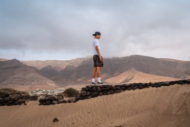 Genç adam Famara plajını ziyaret ediyor. Teg giyin. Lanzarote. Kanarya Adaları. İspanya