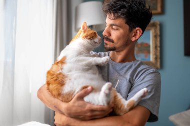 Genç adam evcil kediyle oturma odasında iletişim kuruyor.