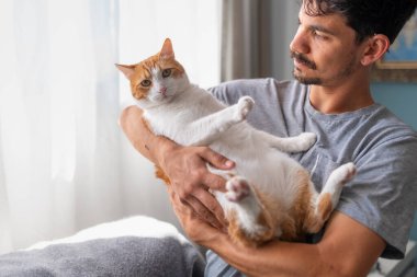 Genç adam evcil kediyle oturma odasında iletişim kuruyor.