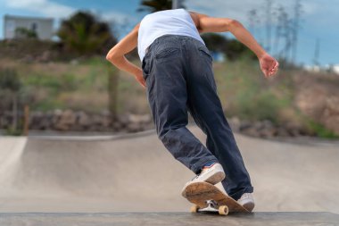 Genç kaykaycı kaykay parkında rampadan atlıyor..