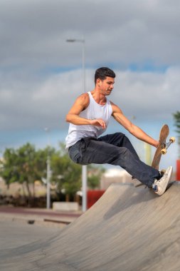 Kaykay parkında rampadan atlayan genç bir kaykaycı. dikey bileşim