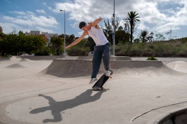 Genç kaykaycı kaykay parkında rampadan atlıyor.. 