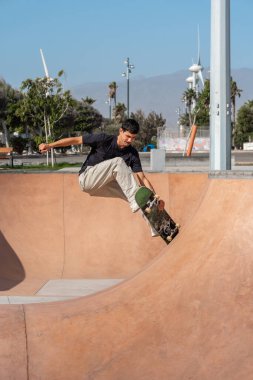 Güneşli bir günde Arinaga kaykay parkında siyah tişört giyen genç bir kaykaycı.