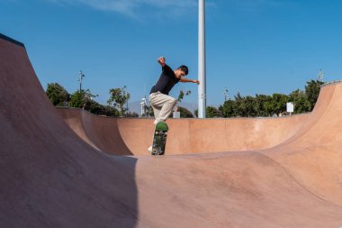 young skater wearing black tshirt skating in Arinaga skate park in a sunny day clipart