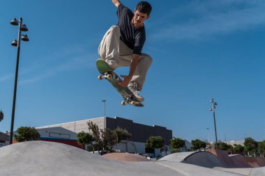 young skater wearing black tshirt skating in Arinaga skate park in a sunny day clipart