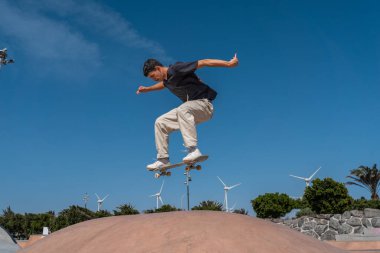 young skater wearing black tshirt skating in Arinaga skate park in a sunny day clipart