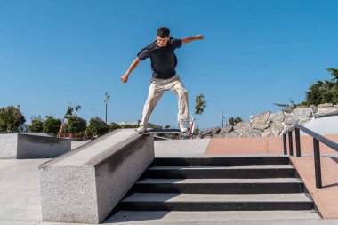 Güneşli bir günde Arinaga kaykay parkında siyah tişört giyen genç bir kaykaycı.