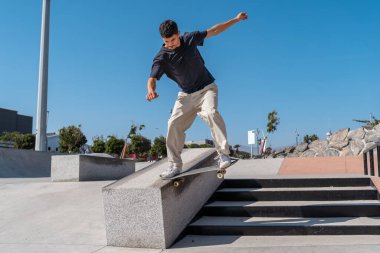 Güneşli bir günde Arinaga kaykay parkında siyah tişört giyen genç bir kaykaycı.