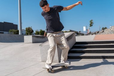 Güneşli bir günde Arinaga kaykay parkında siyah tişört giyen genç bir kaykaycı.