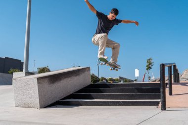Güneşli bir günde Arinaga kaykay parkında siyah tişört giyen genç bir kaykaycı.