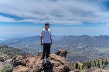 Güneşli bir günde Gran Canaria Adası 'nın tepesinde yürüyüş yapan genç bir adam. Kanarya adaları. İspanya