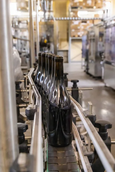 Tmavé Skleněné Láhve Naplněné Vínem Průmyslovým Plnícím Strojem Moderní Vinotéce — Stock fotografie