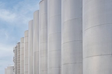 Modern bir şaraphanede şarap fermantasyonu için bir sıra çelik şarap tankı. Geniş bira fabrikası siloları genellikle arpa veya mayalanmış biraları mavi gökyüzüne karşı depolamak için kullanılır.