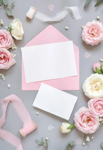 グレーのトップビューにライトピンクのバラとシルクリボンの間の紙カード 結婚式のモックアップ 空の垂直カードとパステルの花のフラットレイとロマンチックなシーン バレンタイン 春や母の日のコンセプト — ストック写真