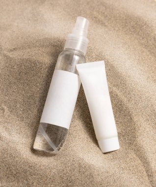 Cream bottles with blank label on beige sand close up. Package mockup. Natural skincare or SPA product. Facial cosmetics for beauty routine. Zen style with waves on sand, minimal 
