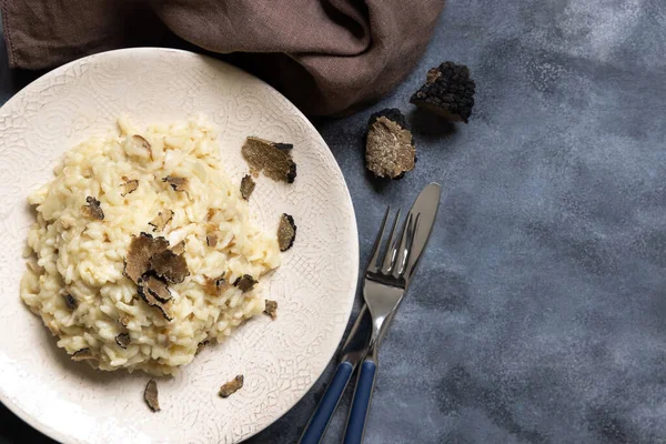 Stock image Risotto with wild porcini mushrooms and black truffles from Italy served in a plate top view on grey table, copy space. Eating Italian gourmet cousine