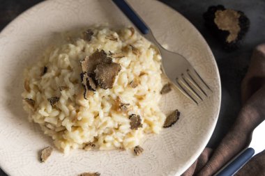 İtalyan mantarlı ve siyah mantarlı risotto gri masada yakın bir tabakta servis edilir. İtalyan gurme kuzeni yemek.