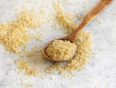 Wooden spoon of Dry uncooked bulgur wheat grain close up, copy space. Vegetarian and Vegan, Mediterranean and Middle Eastern cuisine. Healthy lifestyle