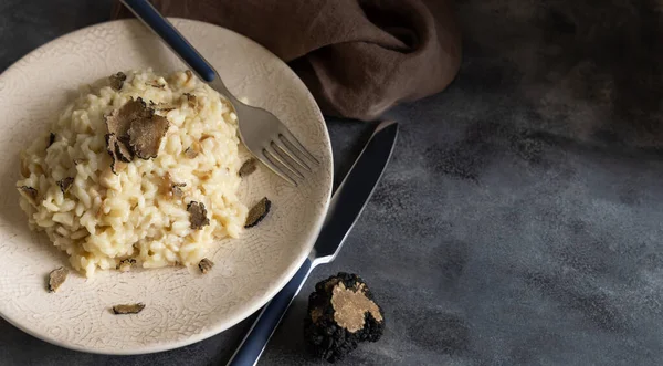 stock image Risotto with wild porcini mushrooms and black truffles from Italy served in a plate close up on grey table, copy space. Eating Italian gourmet cousine