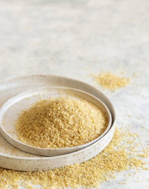 Raw Dry bulgur wheat grain on a white plate on a table close up, copy space. Vegetarian and Vegan, Mediterranean and Middle Eastern cuisine. Healthy lifestyle
