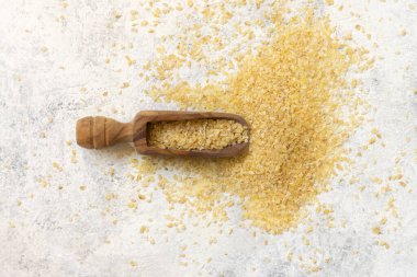 Tahta kepçe, pişmemiş bulgur buğday tohumu üst görünümü, kopyalama alanı. Vejetaryen ve vejetaryen, Akdeniz ve Orta Doğu mutfağı. Sağlıklı yaşam tarzı