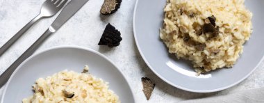 Risotto with wild porcini mushrooms and black truffles from Italy served in a plate top view on white table, copy space. Eating Italian gourmet cousine