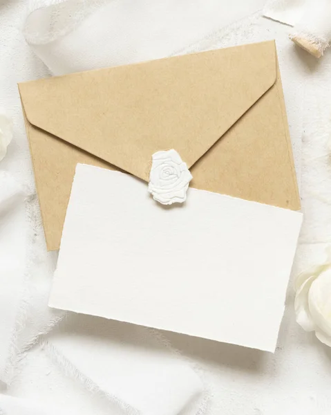 在奶油玫瑰和白色丝带旁边的空白卡片和信封顶视图 婚纱造型 浪漫的场景与垂直卡片和油腻的花朵平铺在一起 情人节 春天或母亲节的概念 — 图库照片