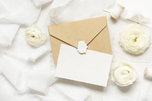 在奶油玫瑰和白色丝带旁边的空白卡片和信封顶视图 婚纱造型 浪漫的场景与垂直卡片和油腻的花朵平铺在一起 情人节 春天或母亲节的概念 — 图库照片