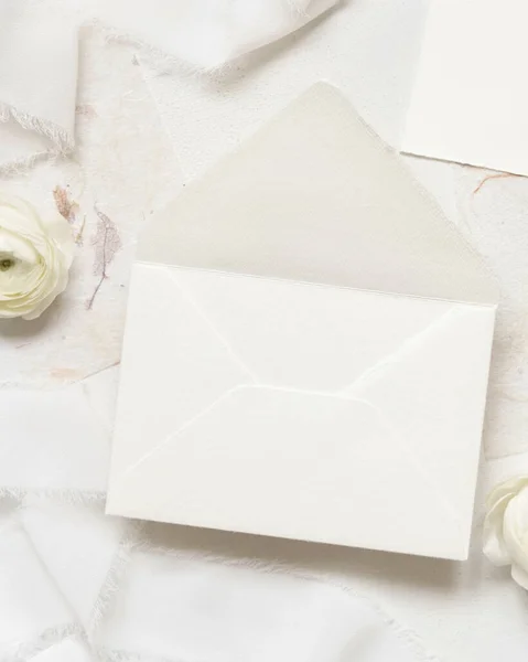 奶油玫瑰和白色丝带旁边的空白信封顶视图 婚纱造型 浪漫的一幕 用淡淡的花朵平铺着 情人节 春天或母亲节的概念 — 图库照片