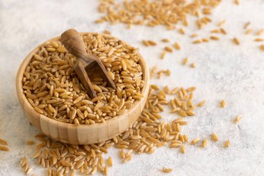 Beyaz masada tahta kaşıkla bir kase çiğ çavdar tohumu. Sağlıklı alternatif düşük glüten tohumları. Vejetaryen ve vejetaryen diyeti için protein kaynağı. 