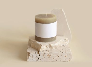 Krem rengi travertin taşların yanında etiketli mum, kapat, kopyala uzayı. Marka paketleme modeli. Ev dekorasyonu, minimal iç dekorasyon, Bohem ya da İskandinav stili