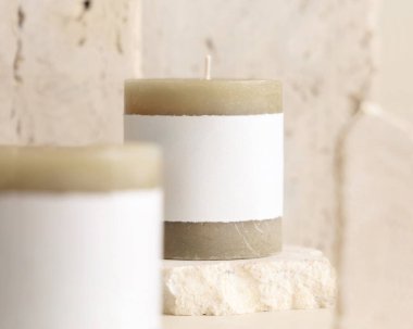 Krem rengi travertin taşların yanında etiketli mumlar. Kapatın, kopyalayın. Marka paketleme modeli. Ev dekorasyonu, minimal iç dekorasyon, Bohem ya da İskandinav stili