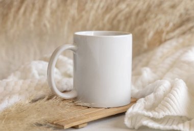 Beyaz kahve fincanı ahşap tepside, otların yanında ve rahat örülmüş süveter yakın, kopyalama alanı. Boho ambalajlama modeli. Bohem, etnik ya da İskandinav tarzı.