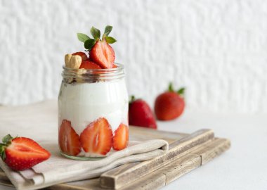 Cam kavanoz Yunan yoğurdu, fındık ve çilek bir tepside peçeteyle, yakın çekim, kopyalama alanı. Meyveli ve fındıklı sağlıklı kahvaltı. Protein yemek için harika bir yol.