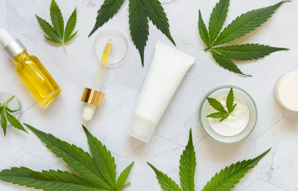 Garrafas Cosméticos Frascos Tubos Com Etiqueta Branco Perto Folhas Cannabis — Fotografia de Stock